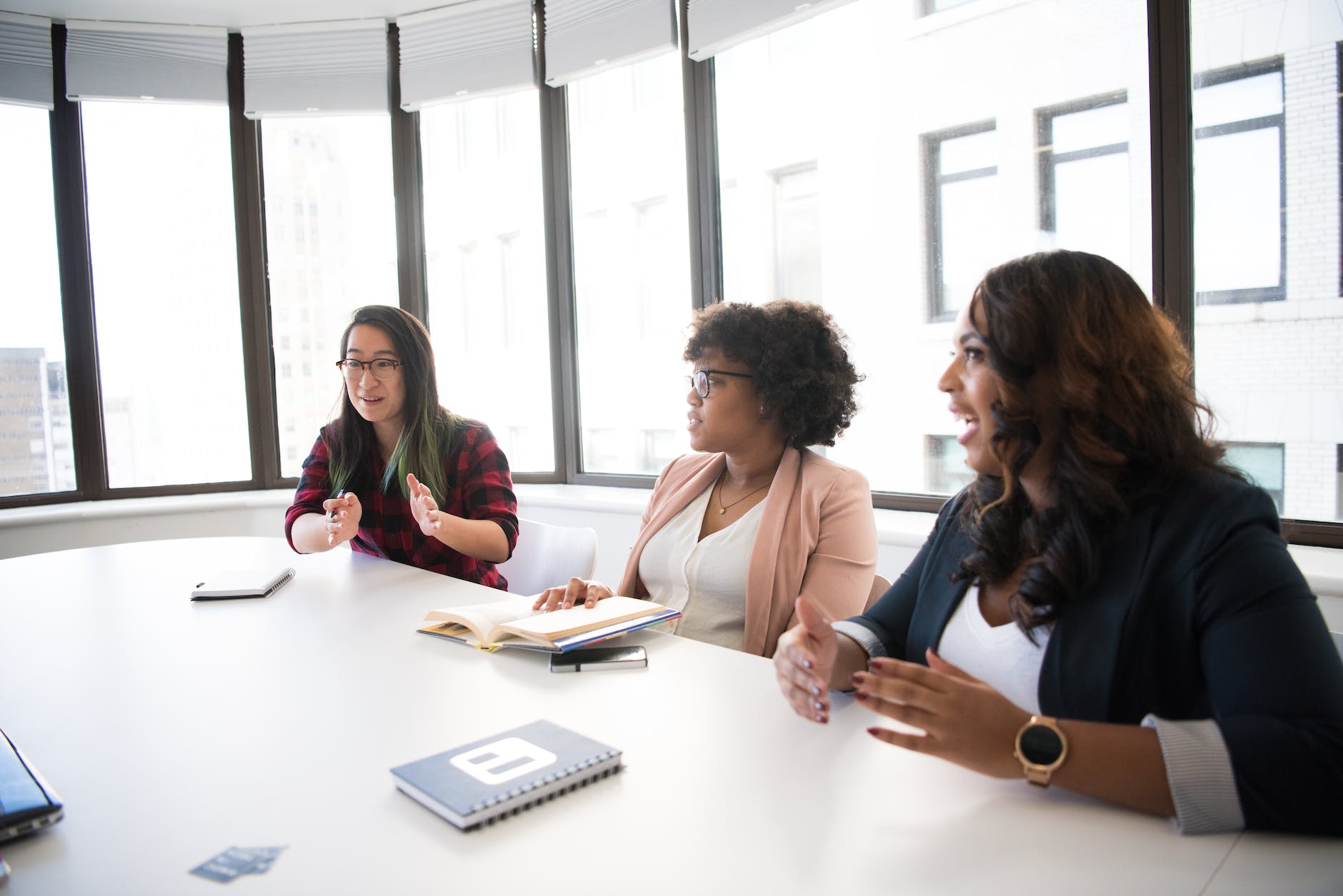 three woman talking near white wooden table inside room